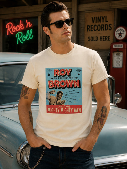 A man wearing a cream-colored graphic t-shirt with a vintage-style Roy Brown poster print, standing in front of a classic car and a rustic wooden sign.